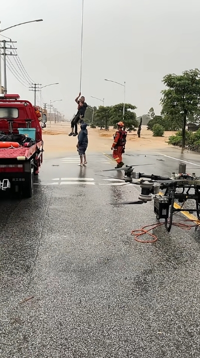 救援人員在道路上接應無人機吊掛的受困者